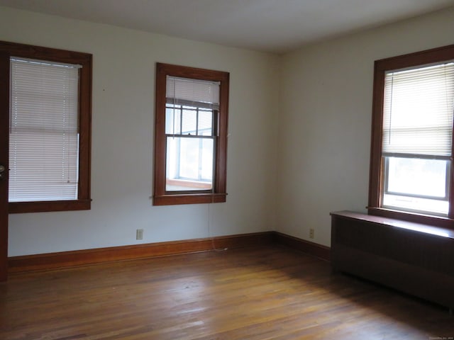 empty room featuring hardwood / wood-style flooring, radiator heating unit, and a wealth of natural light