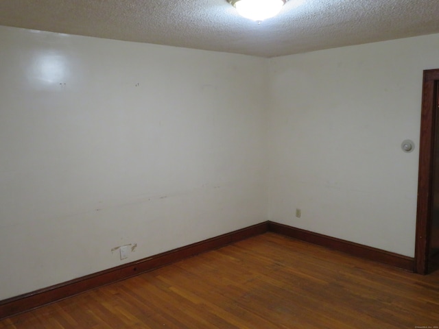 empty room featuring a textured ceiling and dark wood-type flooring