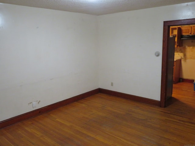 empty room featuring a textured ceiling and dark hardwood / wood-style flooring