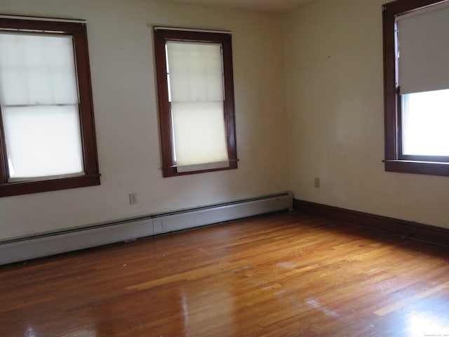 empty room featuring light wood-type flooring and a baseboard heating unit