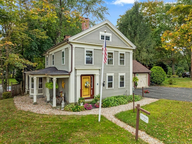 view of front of home featuring a garage, a front lawn, and an outbuilding