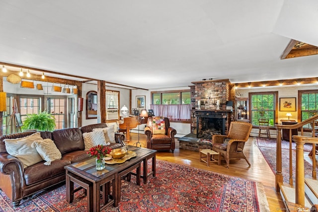 living room with a baseboard radiator, a brick fireplace, a wealth of natural light, and hardwood / wood-style flooring