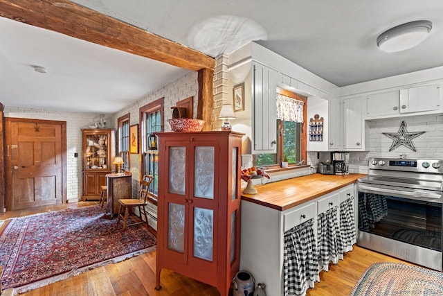 kitchen featuring white cabinetry, brick wall, wooden counters, light hardwood / wood-style flooring, and stainless steel electric range oven