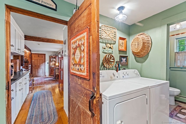 laundry area featuring light wood-type flooring, baseboard heating, and independent washer and dryer