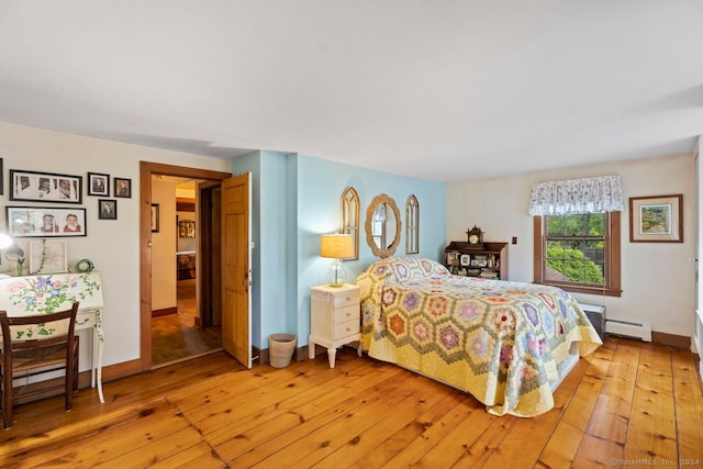 bedroom with light hardwood / wood-style flooring and baseboard heating