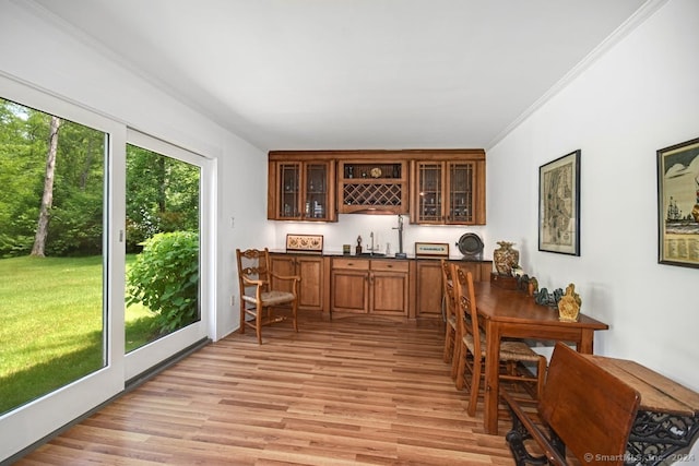 bar with sink, light hardwood / wood-style flooring, and ornamental molding