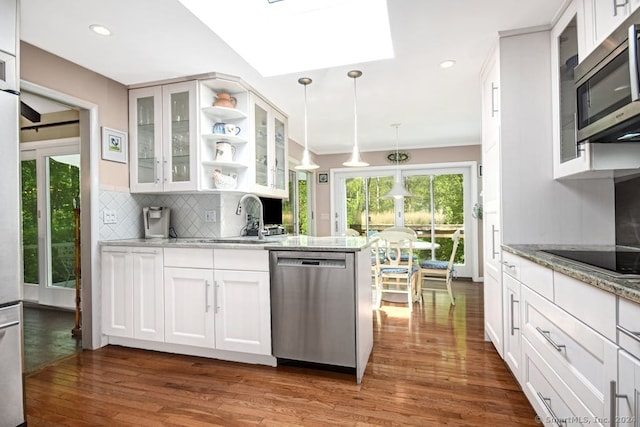 kitchen with light stone counters, appliances with stainless steel finishes, decorative light fixtures, and white cabinets