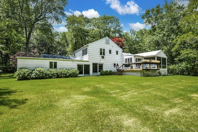 back of house with a wooden deck, a sunroom, and a lawn