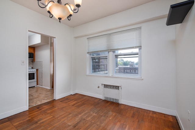 spare room with radiator, dark hardwood / wood-style floors, and a chandelier