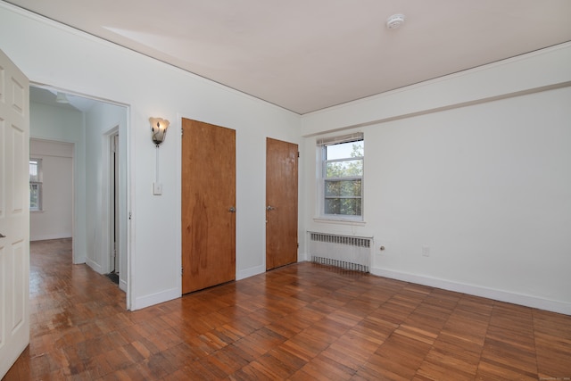 unfurnished bedroom with radiator and dark hardwood / wood-style floors