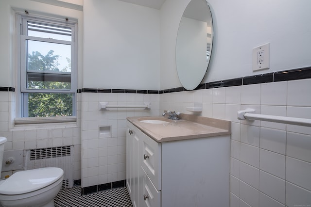 bathroom featuring tile walls, vanity, toilet, and radiator heating unit