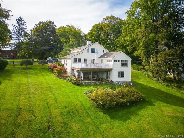 rear view of house with a wooden deck and a lawn