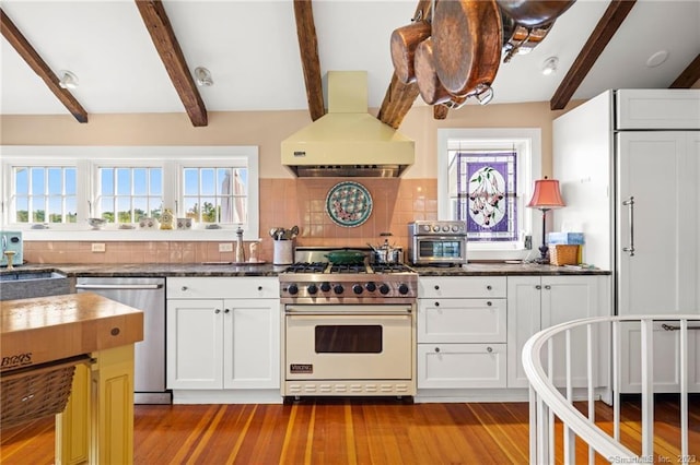 kitchen featuring appliances with stainless steel finishes, exhaust hood, decorative backsplash, and white cabinets