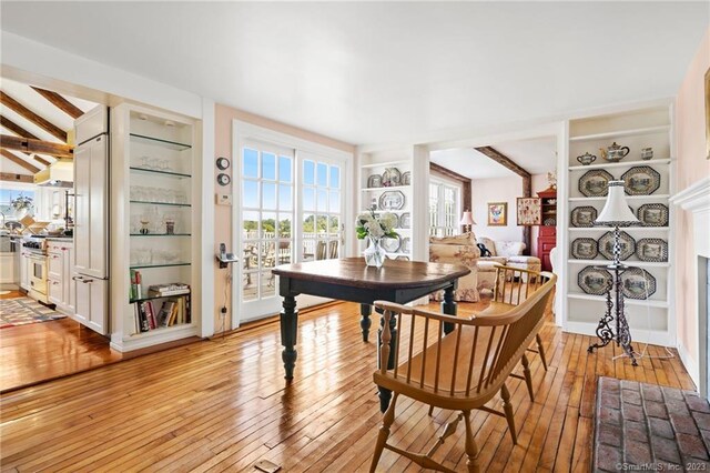 dining room featuring beam ceiling, built in features, and light hardwood / wood-style floors