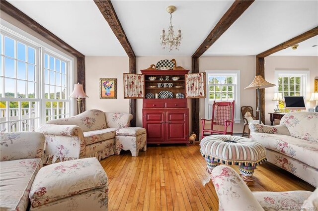 living room featuring beamed ceiling, a chandelier, and light wood-type flooring