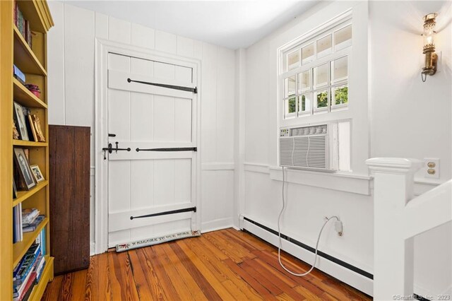 doorway featuring cooling unit, a baseboard heating unit, and wood-type flooring