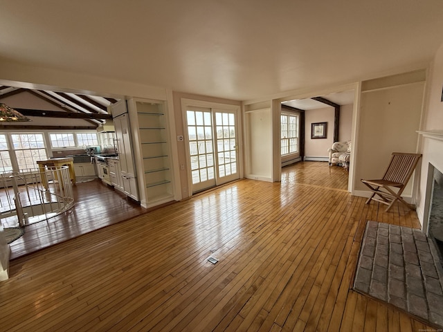 unfurnished living room with hardwood / wood-style flooring, beam ceiling, and baseboard heating