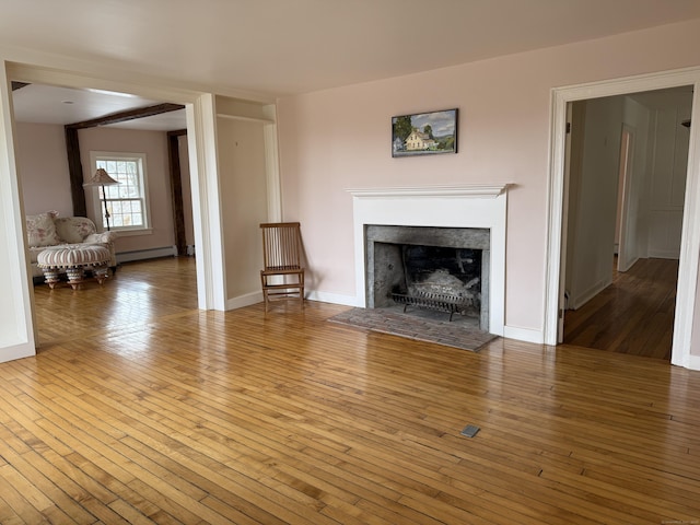 unfurnished living room featuring hardwood / wood-style flooring and baseboard heating