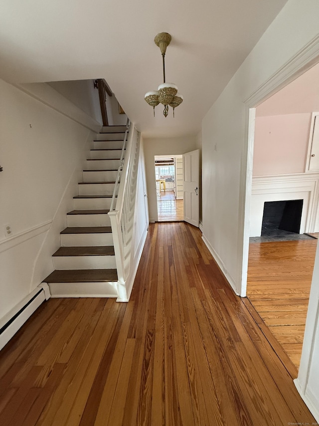 interior space featuring hardwood / wood-style flooring, a baseboard radiator, and a chandelier