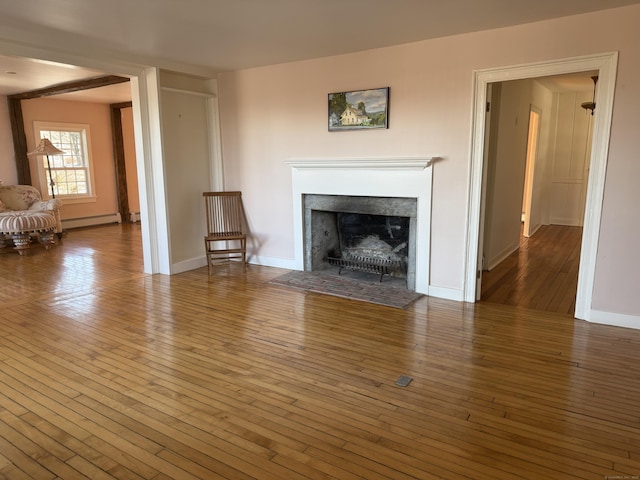 unfurnished living room featuring wood-type flooring and baseboard heating