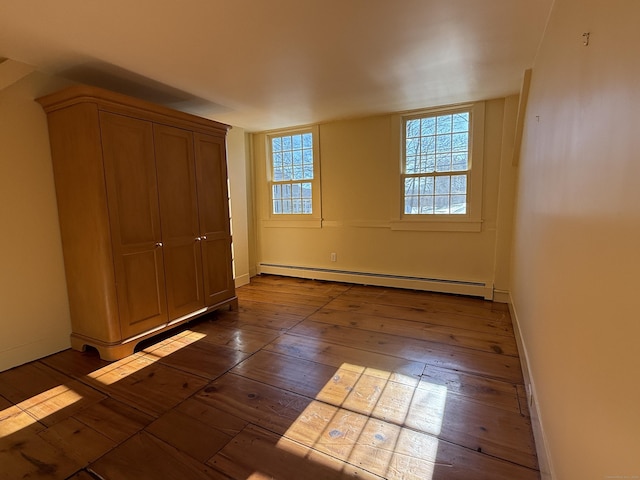 unfurnished bedroom featuring multiple windows, a baseboard radiator, and dark hardwood / wood-style floors