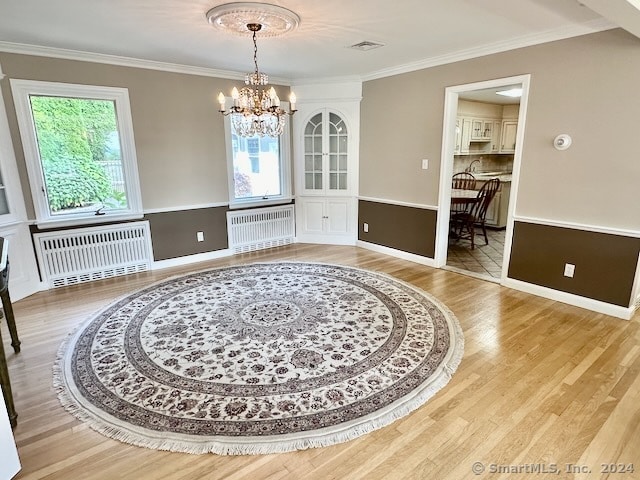 dining area featuring radiator heating unit, wood-type flooring, and plenty of natural light