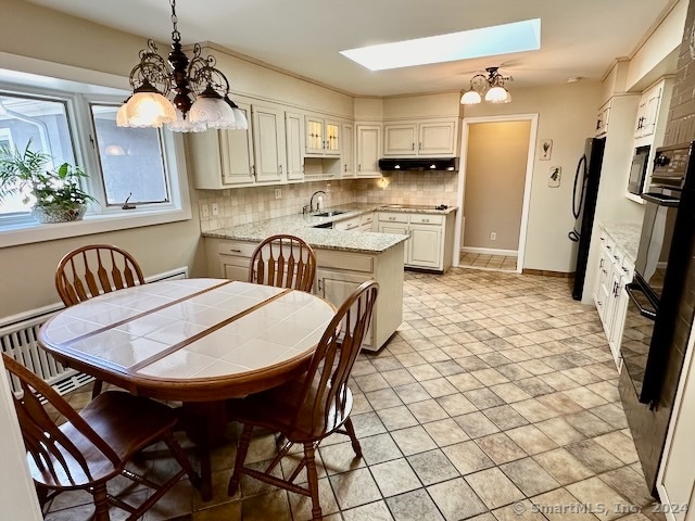 kitchen with hanging light fixtures, decorative backsplash, kitchen peninsula, a skylight, and a chandelier