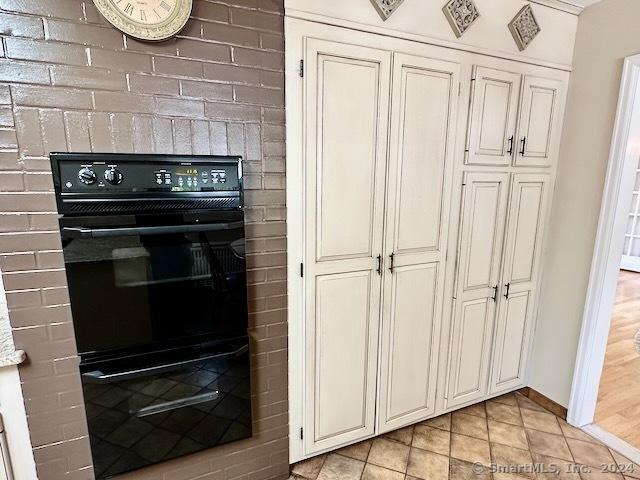 kitchen with light hardwood / wood-style flooring, brick wall, and black double oven