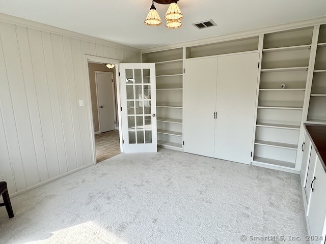 unfurnished bedroom with wooden walls, light colored carpet, and a closet