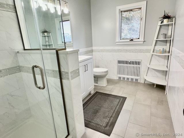 bathroom with radiator, plenty of natural light, vanity, and toilet