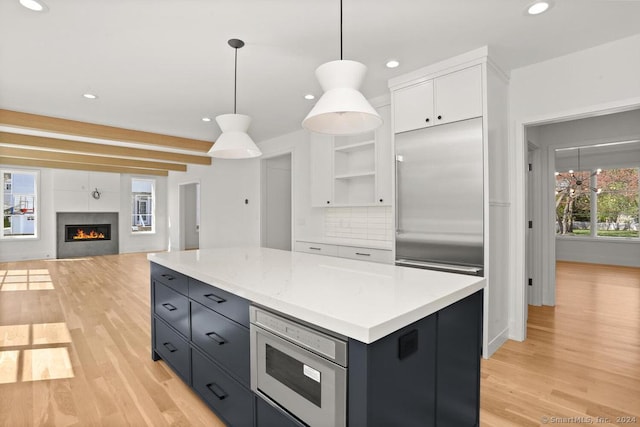 kitchen featuring white cabinets, light wood-type flooring, decorative light fixtures, and tasteful backsplash