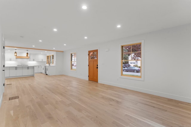 unfurnished living room featuring sink and light wood-type flooring