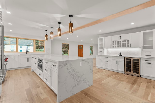 kitchen with stainless steel appliances, wine cooler, decorative light fixtures, a kitchen island, and white cabinets