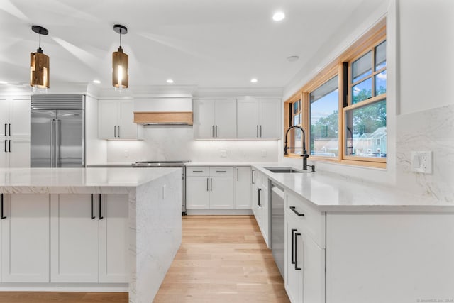 kitchen with stainless steel appliances, light wood-type flooring, white cabinetry, hanging light fixtures, and sink