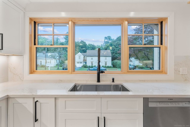 kitchen with tasteful backsplash, stainless steel dishwasher, light stone countertops, and white cabinets