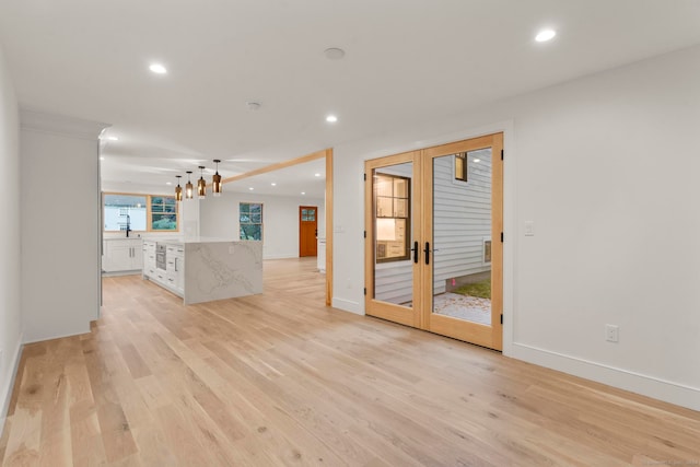 unfurnished living room with light hardwood / wood-style floors and french doors