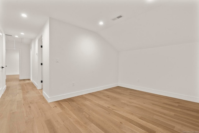 additional living space with light hardwood / wood-style flooring and vaulted ceiling