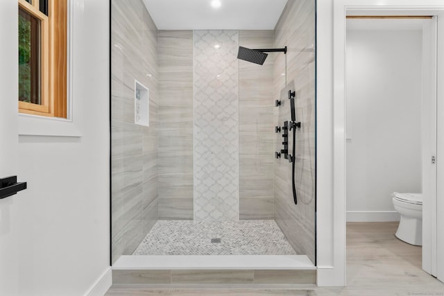 bathroom featuring hardwood / wood-style floors, tiled shower, and toilet