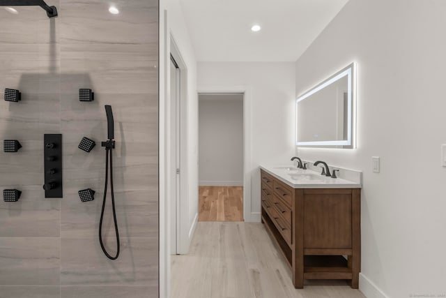 bathroom featuring tiled shower, hardwood / wood-style floors, and vanity