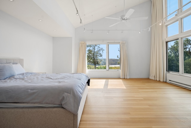 bedroom featuring ceiling fan, light hardwood / wood-style floors, high vaulted ceiling, and rail lighting