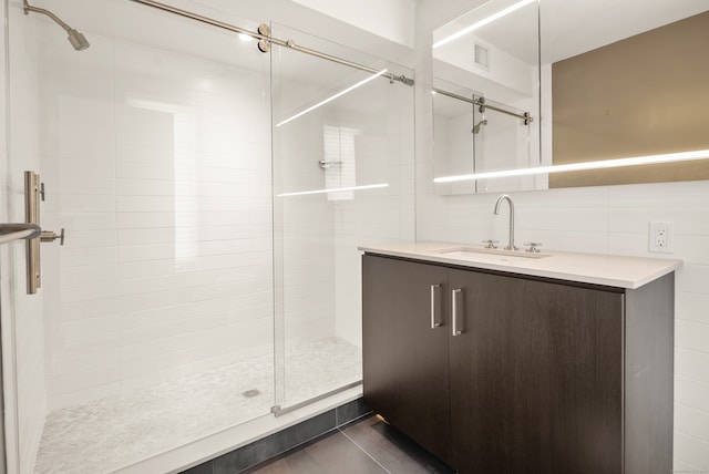 bathroom featuring tile walls, backsplash, vanity, and a shower with door