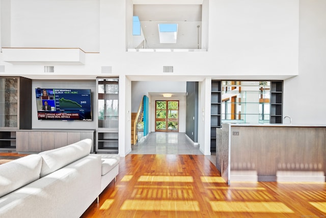 unfurnished living room with hardwood / wood-style flooring, sink, and a high ceiling