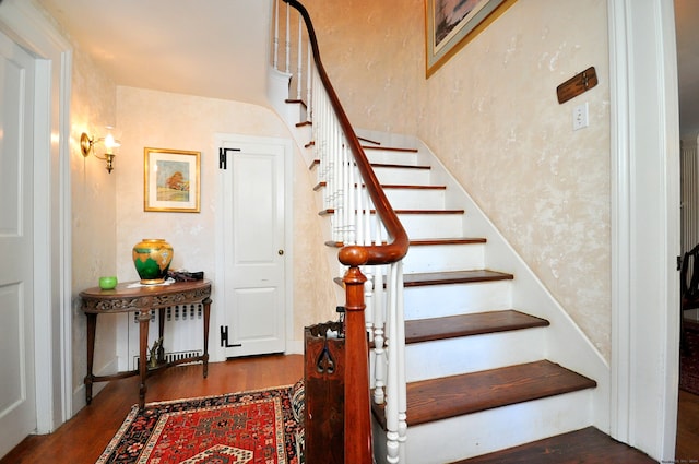 stairway featuring radiator heating unit and hardwood / wood-style flooring