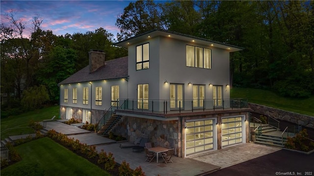 view of front of house with a patio, a lawn, and a balcony