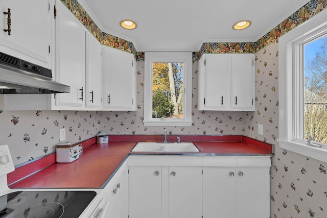 kitchen with white cabinets, range, sink, and ornamental molding