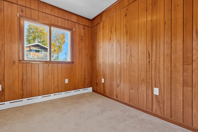 carpeted empty room with wooden walls and a baseboard heating unit