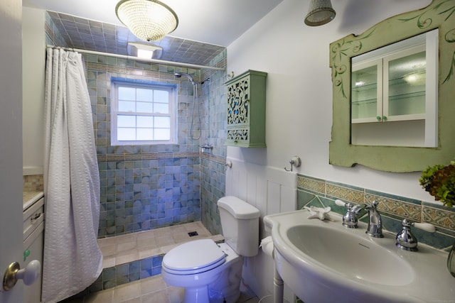 bathroom with curtained shower, sink, tile walls, and toilet