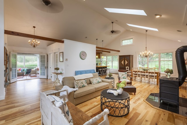 living room featuring a wood stove, a wealth of natural light, and ceiling fan with notable chandelier