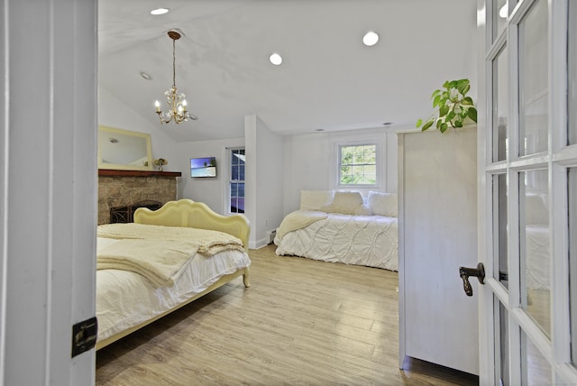 bedroom with a chandelier, vaulted ceiling, and hardwood / wood-style flooring