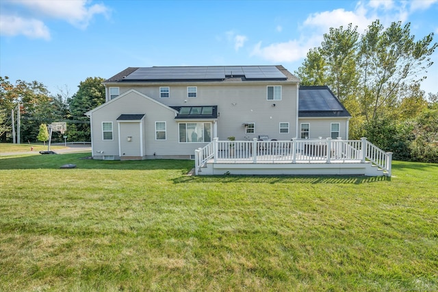 rear view of house featuring a wooden deck, solar panels, and a yard